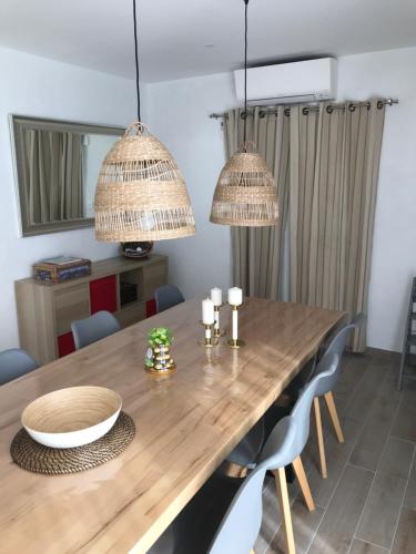 a dining room with a wooden table and two chandeliers at Les Agapanthes in Noirmoutier-en-l'lle