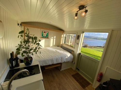 a small bedroom with a bed and a window at Shepherds Hut, Conwy Valley in Conwy