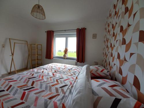 a bedroom with a bed with a comforter and a window at Au Natur'helpe in Momignies