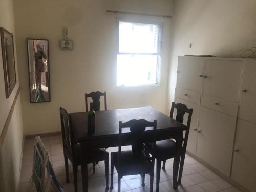 una sala da pranzo con tavolo, sedie e finestra di Apartamento no edifício Abaeté a Mongaguá