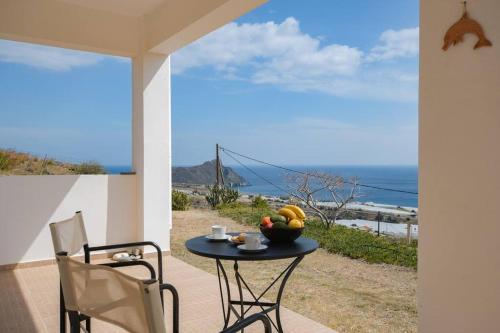 a table with a bowl of fruit sitting on a patio at Angelika House -Amazing Sea view in Moírai