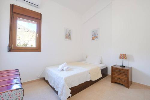 a white bedroom with a bed and a window at Angelika House -Amazing Sea view in Moírai