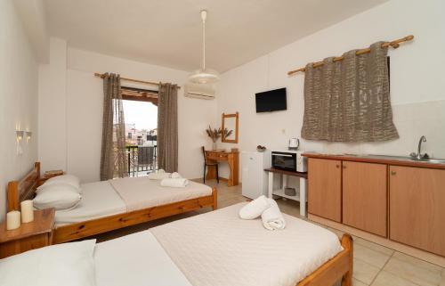 a bedroom with two beds and a kitchen with a sink at Tsimiklis Apartments in Finikounta