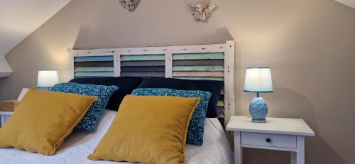 łóżko z niebieskimi i żółtymi poduszkami w pokoju w obiekcie Les Cormiers w mieście Cangey