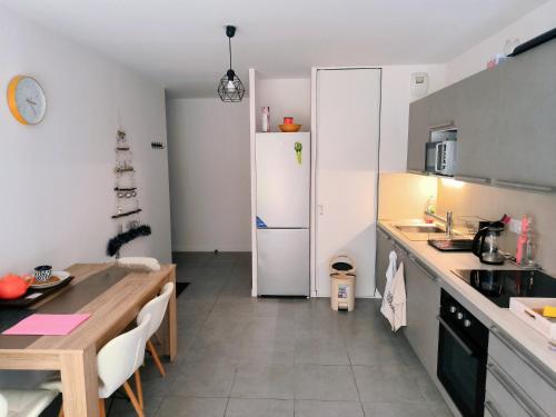 a kitchen with a white refrigerator and a table at Superbe appartement avec jardin in Courrejean