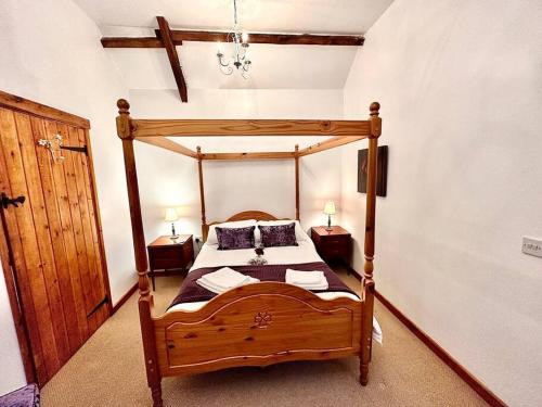 a bedroom with a wooden canopy bed with two night stands at Detached ONE LEVEL stone barn (Rowan Cottage) in Llangwm-isaf