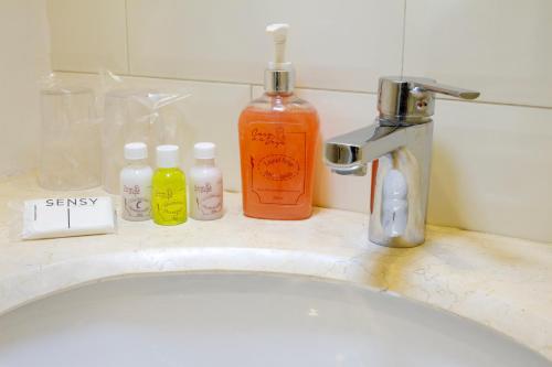 a bathroom sink with bottles of soap and a faucet at Hotel Casa de la Vega in Bogotá