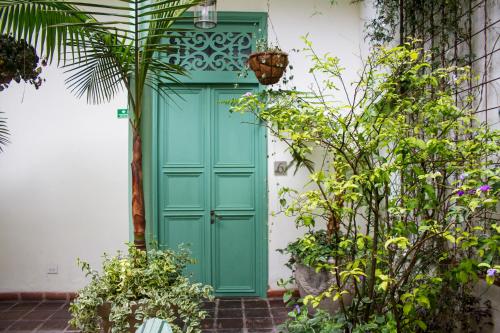 Hotel Casa de la Vega في بوغوتا: باب أخضر على بناية بيضاء فيها نباتات