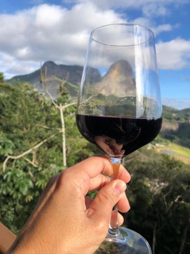a person holding a glass of red wine at Blue Flat Pedra Azul - Com Vista pra Pedra in Pedra Azul