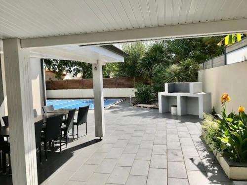 a patio with a table and chairs and a pool at Maison piscine 4 ch Carcans Médoc Bassin Arcachon in Carcans