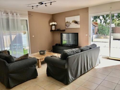 ein Wohnzimmer mit 2 Ledersofas und einem TV in der Unterkunft Maison piscine 4 ch Carcans Médoc Bassin Arcachon in Carcans