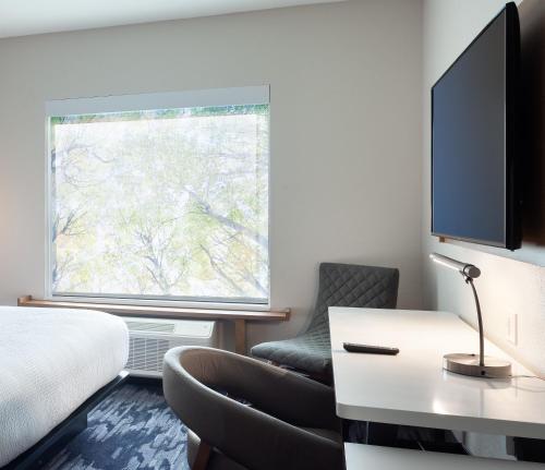 a hotel room with a bed and a tv and a chair at Fairfield Inn & Suites by Marriott Wellington-West Palm Beach in Wellington