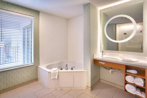 a bathroom with a tub and a sink and a mirror at SpringHill Suites by Marriott Provo in Provo