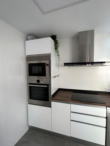 a kitchen with white cabinets and a microwave at Acogedora y moderna casa en pueblo in Serra