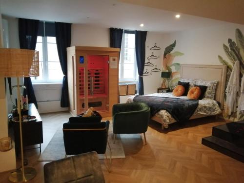 ein Schlafzimmer mit einem Bett und Stühlen in einem Zimmer in der Unterkunft Escapade Mâconnaise Spa-Sauna-Ciel de pluie tropicale-Champagne Nuit Romantique in Mâcon