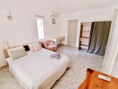 a white bedroom with a bed and a chair at Le Palmier - 4 bedrooms BeachFront villa - Gated Complex in Flic-en-Flac