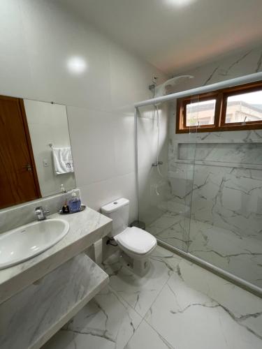 La salle de bains est pourvue de toilettes, d'un lavabo et d'une douche. dans l'établissement Suítes no Paraíso, à Espera Feliz