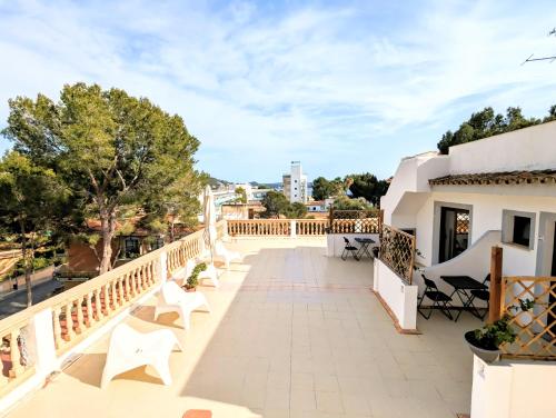 a balcony of a house with white chairs and trees at Don Carlos in Paguera