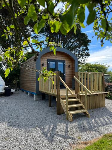 a small cabin with a wooden porch and a wooden stairs at A Unique & Tranquil Smallholding Retreat in Redruth