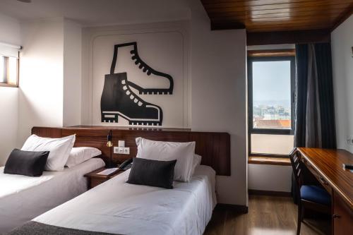 Hotel A.S. Sao Joao da Madeira في ساو جواو دا ماديرا: غرفة في الفندق بسريرين يوجد جزم على الحائط
