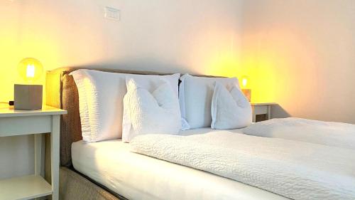 1 dormitorio con 1 cama con sábanas y almohadas blancas en Life Studio & City Bike, en Bolzano