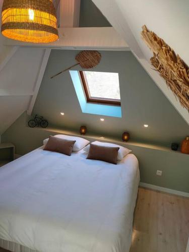 une chambre avec un grand lit blanc dans un grenier dans l'établissement La Closerie de Thimécourt, à Luzarches