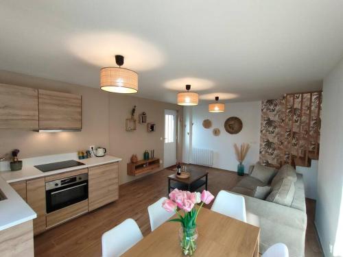 a kitchen and living room with a table with pink flowers at La Closerie de Thimécourt in Luzarches