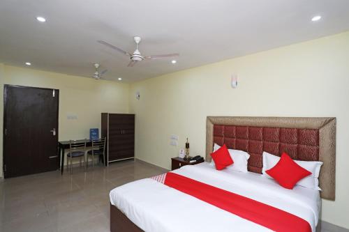 a bedroom with a bed with red pillows and a desk at OYO Ma Classic Inn in Bhubaneshwar