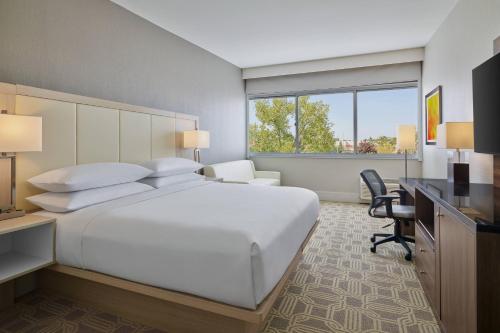 1 dormitorio con 1 cama blanca grande y escritorio en Delta Hotels by Marriott Chicago Willowbrook, en Willowbrook