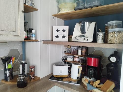a kitchen with a counter with various appliances on shelves at Le Passage du Faubourg, agréable T3 en duplex de 120m2 in Saint-Léonard-de-Noblat