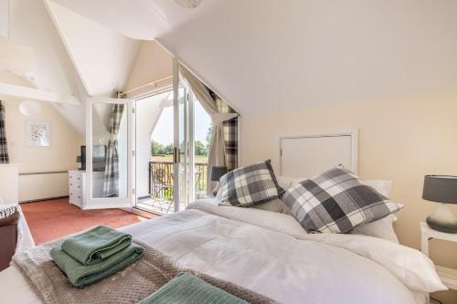um quarto com uma cama e uma grande janela em The Lodge at Alderfen View em Neatishead
