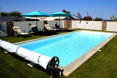 una piscina en un patio con sillas y sombrillas en Les bougainvilliers, en Penta-di-Casinca