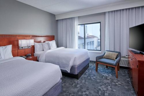 ein Hotelzimmer mit 2 Betten und einem TV in der Unterkunft Courtyard by Marriott Indianapolis Castleton in Indianapolis