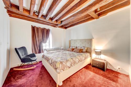 ein Schlafzimmer mit einem Bett und einem Stuhl darin in der Unterkunft Notre-Dame Appartement Familial in Paris
