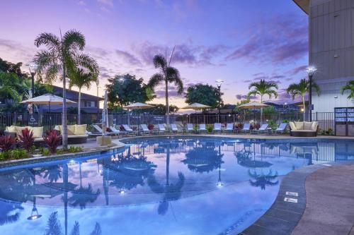 a pool with chairs and palm trees in a resort at Residence Inn by Marriott Oahu Kapolei in Kapolei