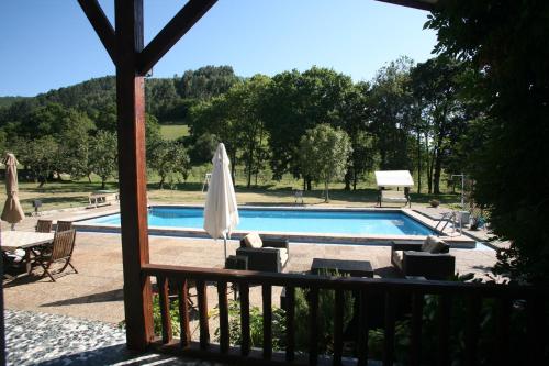 - une piscine avec une table et un parasol dans l'établissement Chalet con piscina en Peón "Los Tres Robles", 
