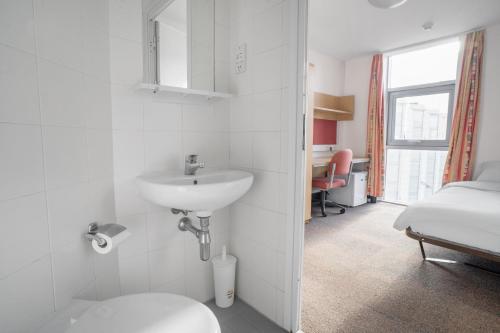 a bathroom with a sink and a bed in a room at Davies Court (Canary Wharf) in London