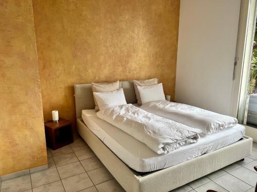 - un lit avec des draps et des oreillers blancs dans l'établissement Wohnung mit Aussicht auf Lago Maggiore & Pool, à Contra