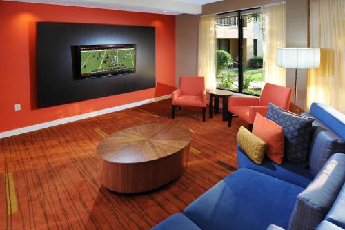 a living room with blue couches and a tv at Courtyard by Marriott Houston Hobby Airport in Houston