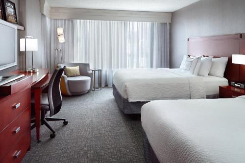 a hotel room with two beds and a desk at Courtyard by Marriott Atlanta Buckhead in Atlanta