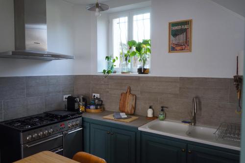 uma cozinha com um fogão e um lavatório em La Bycoque, maison au calme près de Fontainebleau em Thomery