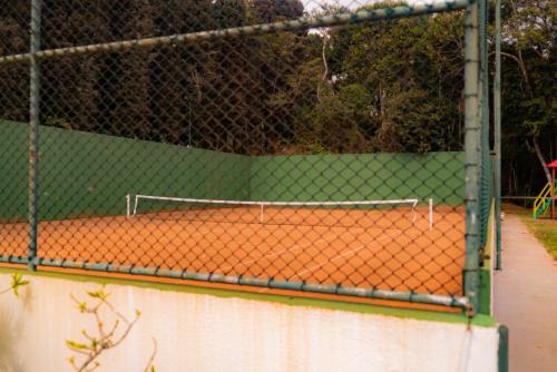 a tennis court with a chain link fence at Blue Flat Pedra Azul - Com Vista pra Pedra in Pedra Azul