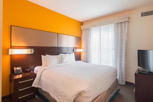 a hotel room with a large bed and a flat screen tv at Residence Inn by Marriott Denton in Denton