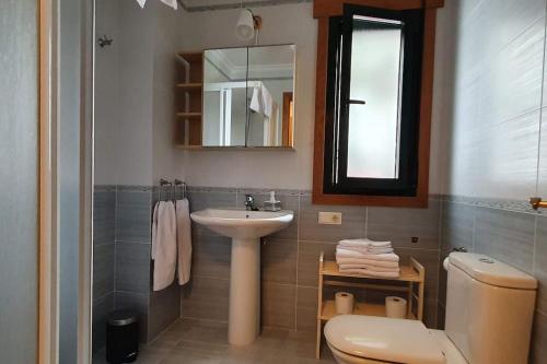 een badkamer met een wastafel, een toilet en een spiegel bij Apartamento playa Llas in Foz