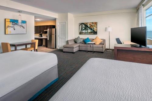 a hotel room with a bed and a living room at Residence Inn Fort Lauderdale Pompano Beach/Oceanfront in Pompano Beach