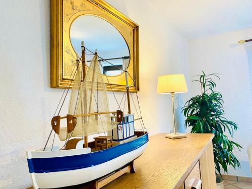ein Holzboot auf einem Schreibtisch mit einem Spiegel in der Unterkunft Barbarahof Ferienwohnung Vita Erdgeschoss in Markdorf