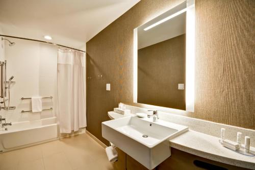 SpringHill Suites by Marriott Cincinnati Blue Ash في بلو أش: حمام مع حوض ومرآة وحوض استحمام