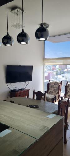 sala de estar con mesa y TV grande en Departamento a 100 mts de playa en Puerto Madryn! en Puerto Madryn