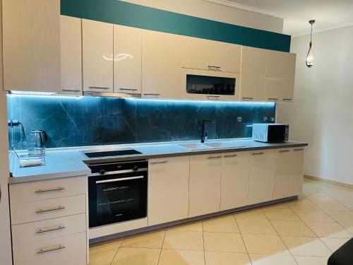 uma cozinha com armários brancos e uma parede azul em eliTe deluxe residence em Kavala