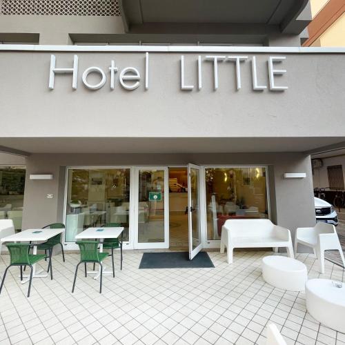 a hotel with tables and chairs in front of a store at Hotel Little in Rimini